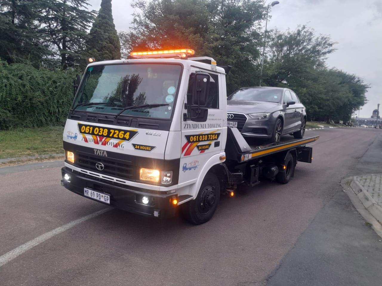 Ziyaduma Towing flatbed truck loaded with a grey Audi sedan, amber beacon on